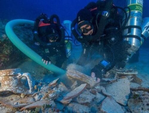 Deux plongeurs explorent des vestiges sous-marins à l’aide d’un tuyau