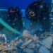 Deux plongeurs explorent des vestiges sous-marins à l’aide d’un tuyau