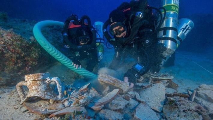 Deux plongeurs explorent des vestiges sous-marins à l’aide d’un tuyau